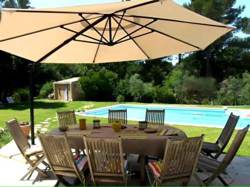 ein Tisch mit Sonnenschirm vor einem Pool in der Unterkunft La Thébaïde in Saint-Marc-Jaumegarde