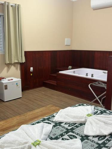 a bathroom with a tub and a bed with towels at Pousada Café em Flor -Quarto Hidromassagem in Inconfidentes