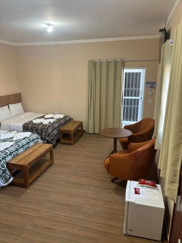 a hotel room with two beds and a chair and a table at Pousada Café em Flor -Quarto Hidromassagem in Inconfidentes