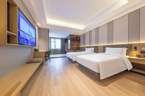 ein Hotelzimmer mit zwei Betten und einem Flachbildfernseher in der Unterkunft Qiuguo Garden Hotel in Dongguan