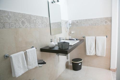 bagno con lavandino, specchio e asciugamani di B&B The Queen a Ispica