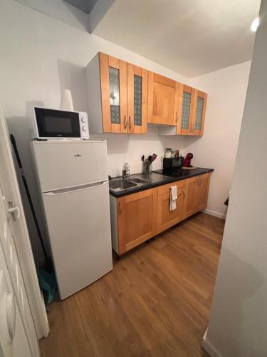a kitchen with a white refrigerator and wooden cabinets at Logement cosy Essonne in Longjumeau
