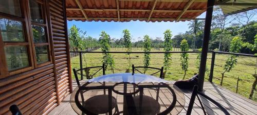 a table and chairs on a porch with a view of a field at Cabañas Retiro Del Rio in Guayabal