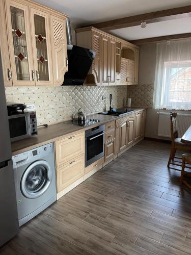a kitchen with wooden cabinets and a washer and dryer at Будинок у Олени in Pochayiv