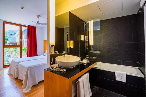 a bathroom with a sink and a tub and a bed at Tierra de Biescas in Biescas