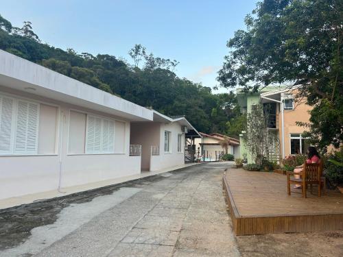 eine Frau sitzt auf einer Terrasse vor einem Haus in der Unterkunft Casa Espaçosa com Piscina, Churrasqueira e Área verde em Sambaqui ao Lado da Praia - Floripa in Florianópolis