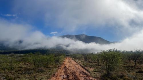 una strada sterrata in mezzo a un campo con le nuvole di Geluk Cottage a Somerset East