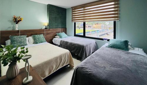 ein Schlafzimmer mit zwei Betten und einem Fenster in der Unterkunft Apartment 7 with Jacuzzi in the center - 3 Bedroom 2 Bath in Baños