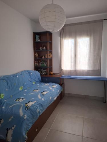 a bedroom with a bed with a blue comforter and a window at El Antiguo Corral de Sevilla in Navalcán