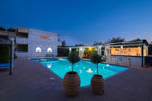 a swimming pool with two potted plants next to a building at Studios Suzanna in Potos
