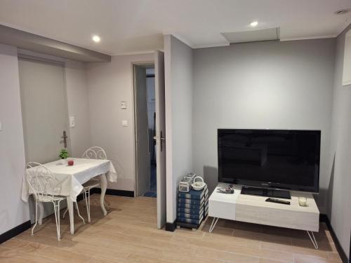 a living room with a tv and a table with chairs at Le Repaire de Belette in Coulounieix-Chamiers