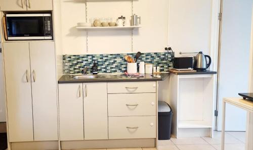 MotungararaCasa de los Tūi的带白色橱柜和水槽的厨房