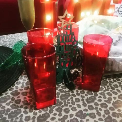three red glasses sitting on a table with a christmas ornament at Fundilhos House in Rio das Ostras