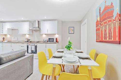 a kitchen and dining room with a white table and yellow chairs at Ocean Walk - By My Getaways - Free Parking in Brighton & Hove