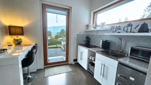 una cucina con mobili bianchi e una grande finestra di The Cube Cow Bay Suite a Cowichan Bay