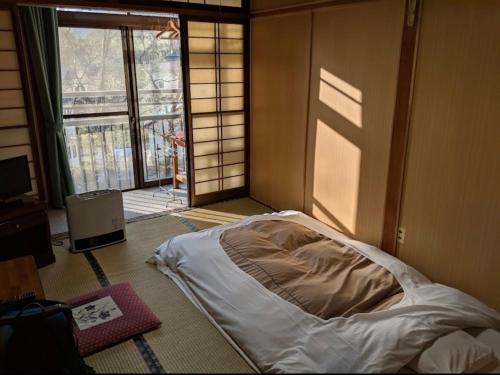 a bedroom with a bed in a room with a window at 天狗の茶屋旅館 in Miyota