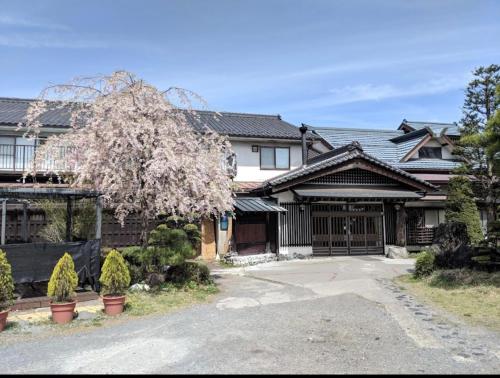 a house with a tree in front of a driveway at 天狗の茶屋旅館 in Miyota