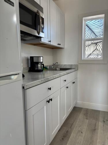 a kitchen with white cabinets and a sink and a window at Holiday Isles Resort in St Pete Beach
