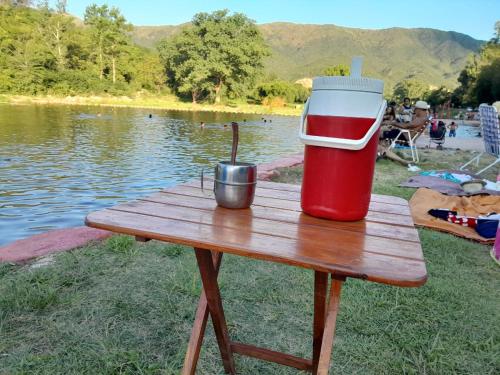 a red and white cooler sitting on a picnic table next to a lake at Mateo y Stella 3 in Bialet Massé