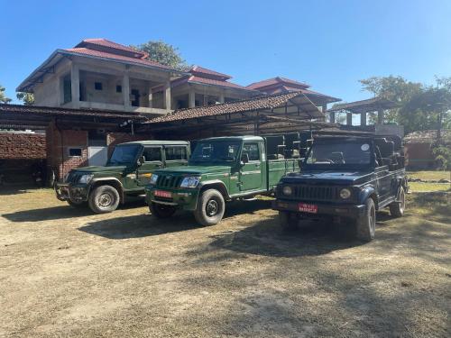 three green trucks parked in front of a house at Bardia Forest Camp in Bardia
