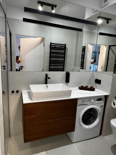 a bathroom with a sink and a washing machine at Apartament Morzlive in Ustronie Morskie