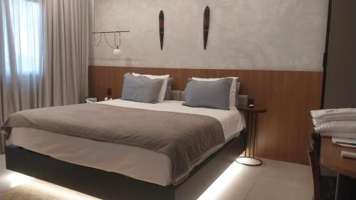una habitación con una cama grande con sábanas y almohadas blancas en Flat JK Luxo, en Ribeirão Preto