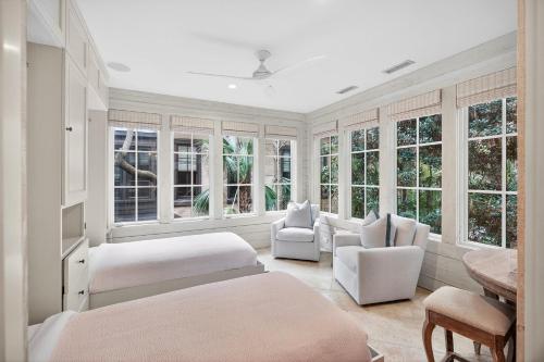 a bedroom with two beds and chairs and windows at 5556 Cypress Point in Kiawah Island