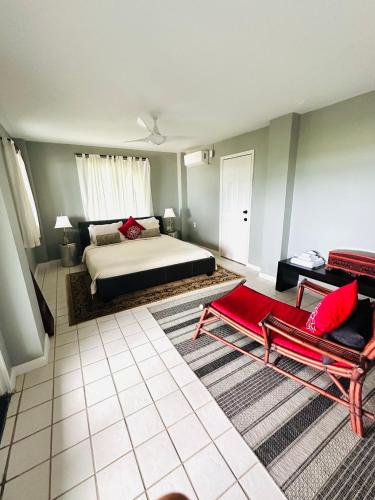 a bedroom with a bed and two red chairs at Featherstone Downstairs Apartment, Cayman Brac in Cayman Brac