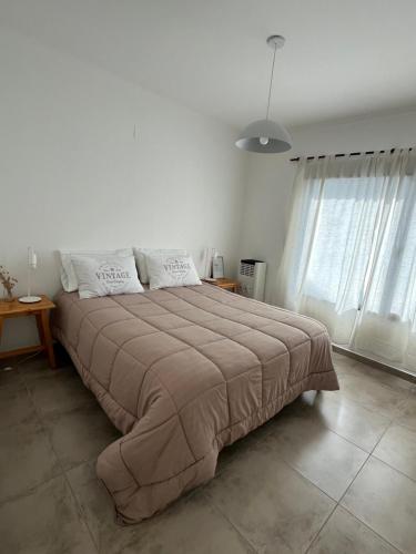 a large bed in a white room with windows at La Elenita Tandil in Tandil