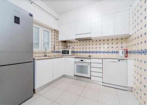 a white kitchen with white cabinets and appliances at 403 - Oura - 2 bedroom- Sea View in Albufeira
