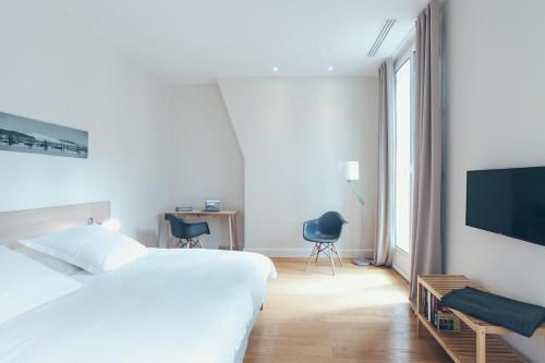 a white bedroom with a bed and a tv at Appartement T4 cours de l'intendance in Bordeaux