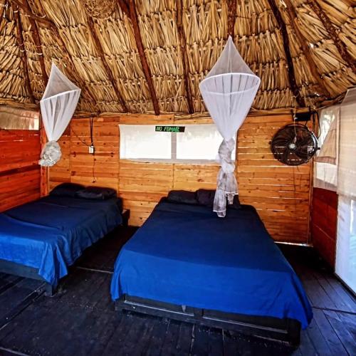 two beds in a room with a straw roof at Casa Balam Sisal in Sisal