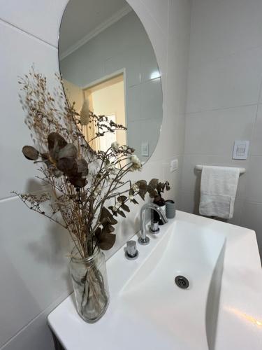 a bathroom sink with a vase with flowers in it at La Elenita Tandil in Tandil