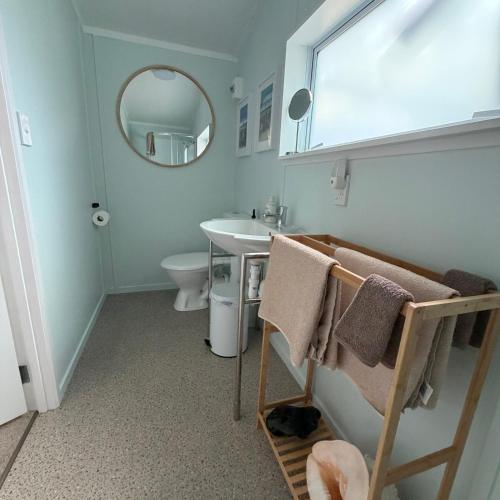 a bathroom with a sink and a toilet and a mirror at Captains Quarters in Ohope Beach