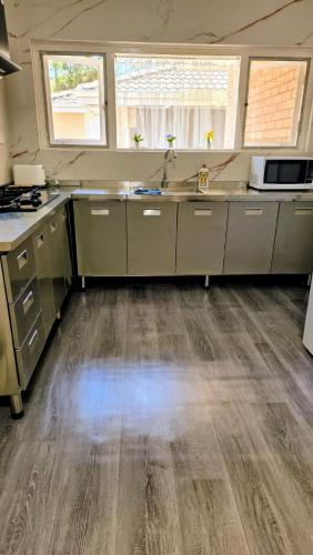 a kitchen with stainless steel appliances and wooden floors at Cozy Room near airport and train station in Perth