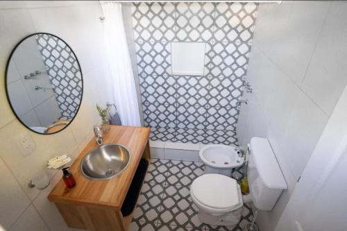 a bathroom with a sink and a toilet and a mirror at Tranqueras al Norte in Chascomús
