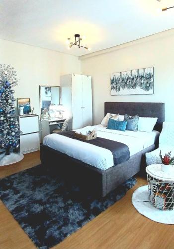 a bedroom with a large bed and a christmas tree at The Lumiére Stays Sophisticated Escape Mallside Charm in Trece Martires