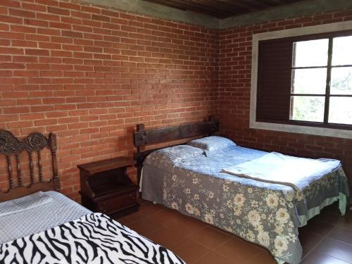 科蒂亚Fazenda do Sonhos - Cotia的一间卧室，有两张床和一堵砖墙