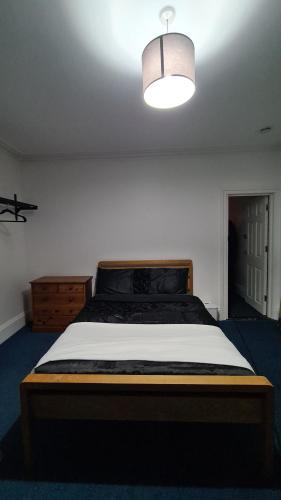 a bedroom with a large bed with a light above it at Supported Guest rooms near Fratton Park in Portsmouth