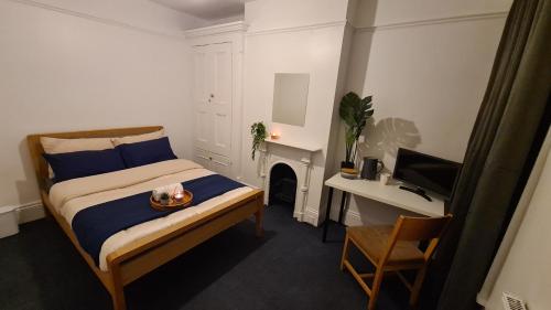 a bedroom with a bed and a desk and a television at Supported Guest rooms near Fratton Park in Portsmouth