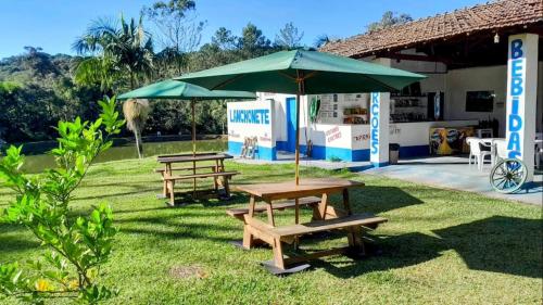 twee picknicktafels en een paraplu in het gras bij Casas de Campo com Piscina, Pesca - Mata Atlântica in Juquitiba