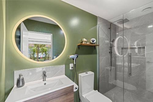 a bathroom with a toilet and a sink and a mirror at City Fringe-Guest House in Christchurch