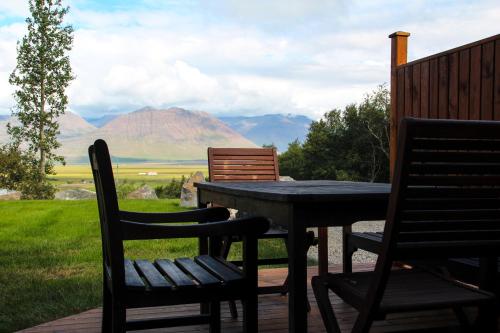 a table and chairs on a patio with mountains in the background at Hestasport Apartment in Varmahlid