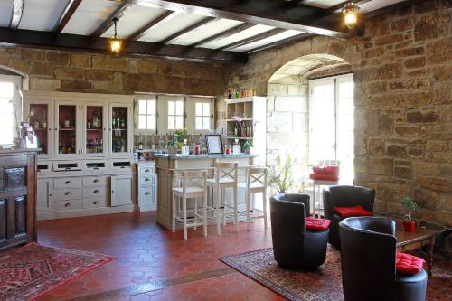 une cuisine avec un comptoir et un bar avec des chaises dans l'établissement Manoir de Moëllien, The Originals Relais (Relais du Silence), à Plonévez-Porzay