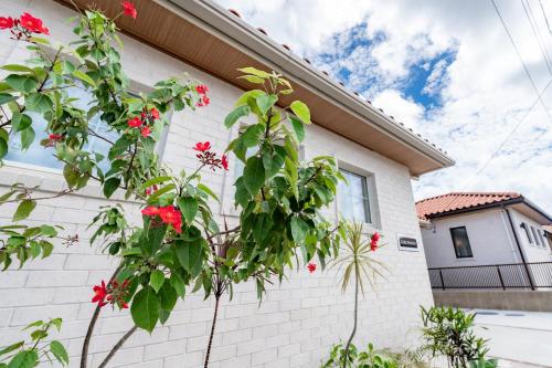 a white brick house with red flowers in front of it at Guel Palacio in Miyako-jima