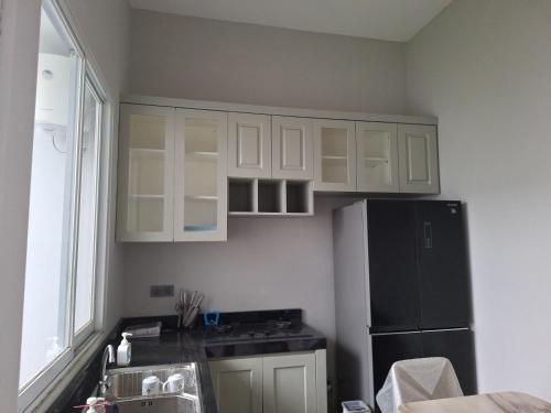 una cucina con mobili bianchi e un frigorifero nero di Cluster Springwood a Pontianak
