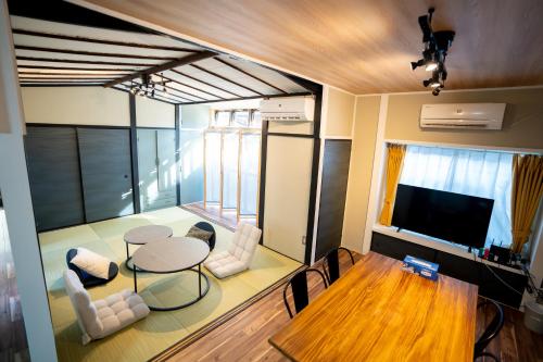a living room with a table and chairs and a television at 縁湯の宿 道後 in Matsuyama