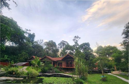 Teratak Jannah Homestay & Resort في كوالا لكانغسار: منزل وسط ساحة فيها اشجار