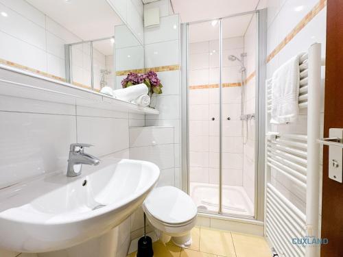 a white bathroom with a sink and a toilet at Lord Nelson Wohnung 118 in Döse