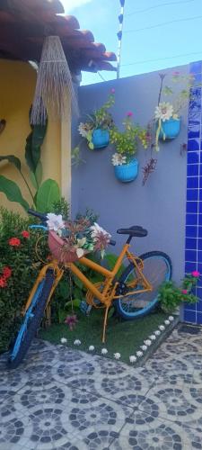 an orange bike parked next to a wall with potted plants at Chalé Aconchego dos Milagres in São Miguel dos Milagres